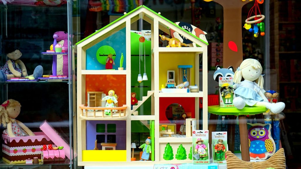 A vibrant dollhouse and stuffed toys displayed in a toy store window, perfect for childrens play.